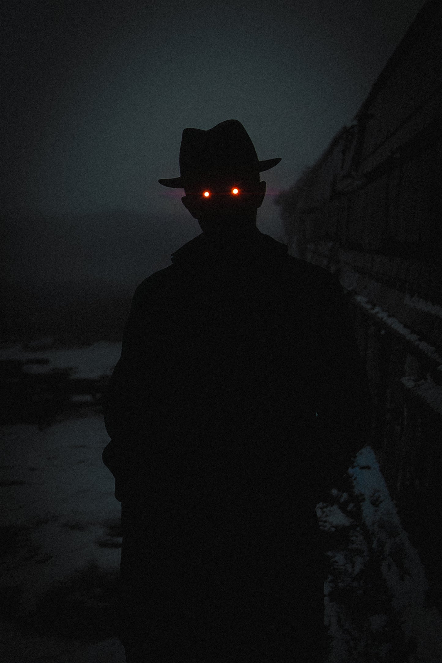 Frostbound Sentinel - the Hat Man, a shadow figure with glowing red eyes standing in the snow beside a train